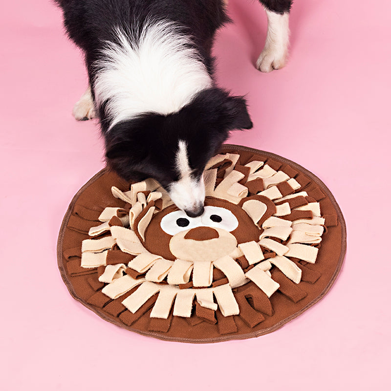 A black and white dog sniffing for treats in a brown and cream lion-face fleece snuffle mat
